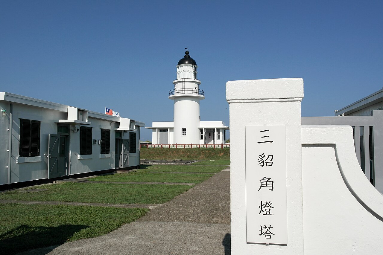 Faro blanco del cabo de Santiago (三貂角燈塔) visto desde la entrada del recinto, con el pilar que lleva su nombre en caracteres chinos